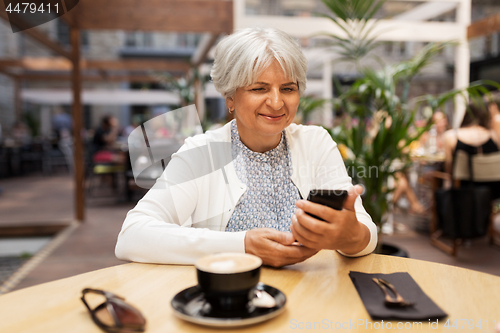 Image of happy senior woman with smartphone at street cafe