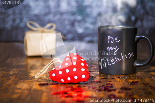 Image of Valentine's day concept with black cup, chalk inscription on a mug and a red heart