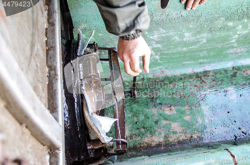 Image of A hand opens a metal barrel with young carp to release fish into the pond