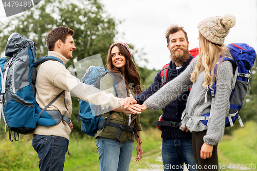 Image of friends with backpacks hiking and stacking hands