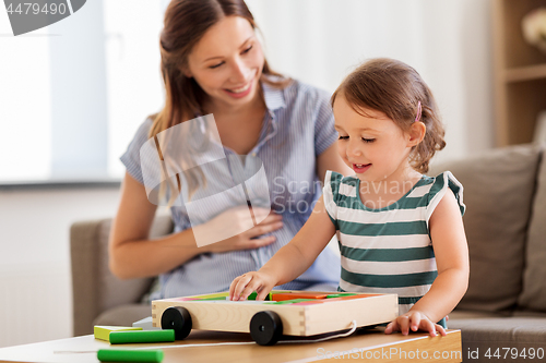 Image of pregnant mother and daughter with toy blocks