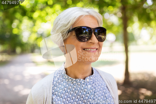 Image of portrait of happy senior woman at summer park