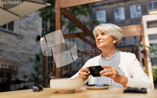 Image of senior woman drinking coffee at street cafe