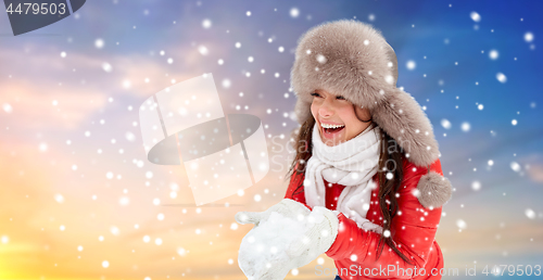 Image of happy woman with snow in winter fur hat outdoors