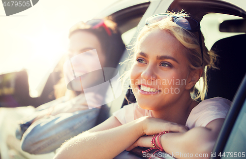 Image of happy teenage girls or women in car at seaside