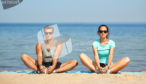 Image of couple stretching legs on beach