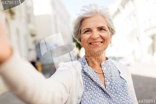 Image of happy senior woman taking selfie on city street