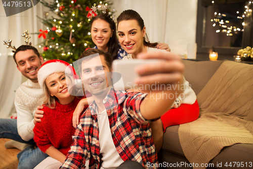 Image of friends celebrating christmas and taking selfie
