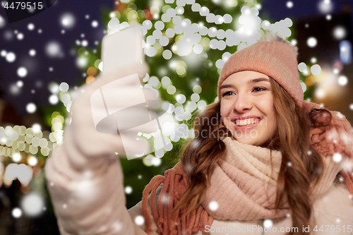 Image of young woman taking selfie over christmas tree