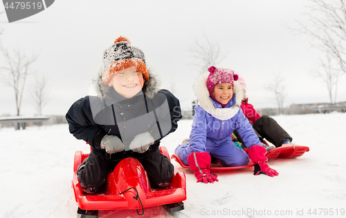 Image of happy little kids sliding down on sleds in winter