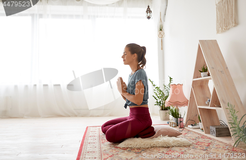 Image of woman meditating in lotus pose at yoga studio