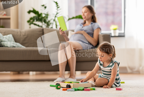 Image of happy baby girl playing with toy blocks at home