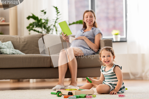 Image of happy baby girl playing with toy blocks at home