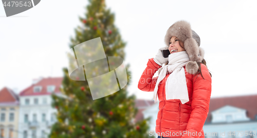 Image of woman calling on smartphone over christmas tree