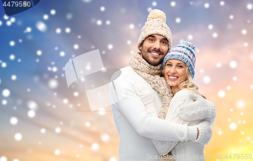 Image of happy couple in winter clothes hugging over snow