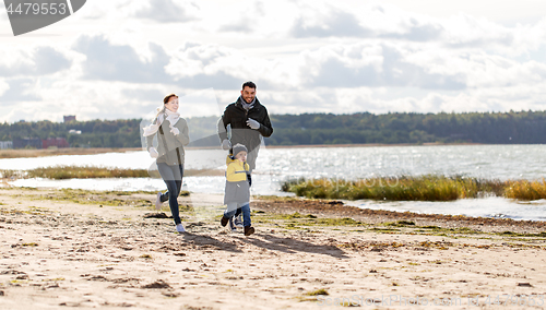 Image of happy family running along autumn beach