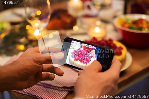 Image of hands photographing food at christmas dinner