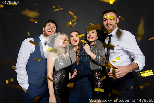 Image of happy friends at party under confetti over black