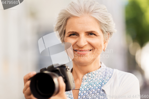 Image of senior woman photographing by digital camera