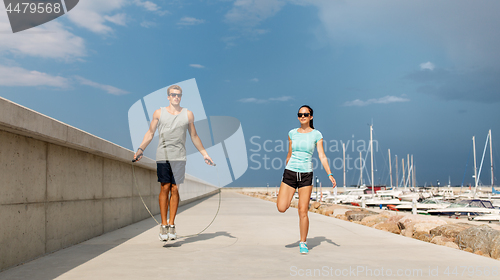 Image of happy couple warming up on pier before training
