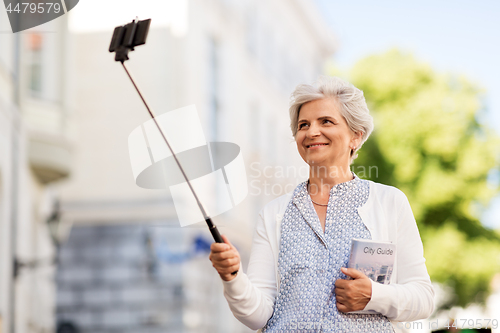 Image of happy senior woman taking selfie on city street