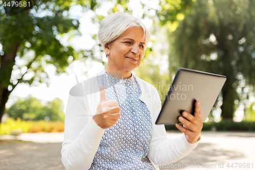 Image of senior woman with tablet pc showing thumbs up