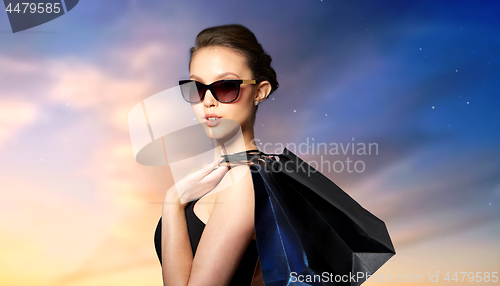 Image of happy woman in black sunglasses with shopping bags