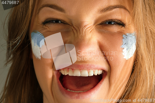 Image of Portrait of a woman with the flag of the Argentina painted on her face.