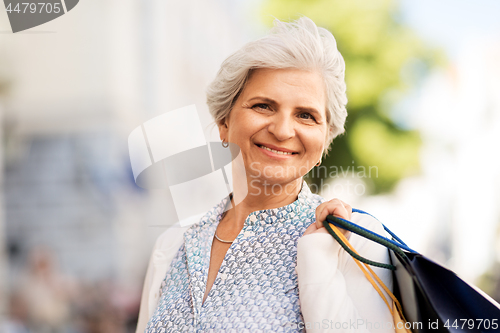 Image of senior woman with shopping bags in city