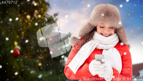 Image of woman with smartphone over christmas tree