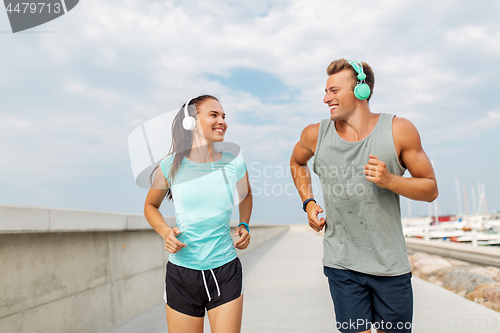 Image of couple with headphones running outdoors