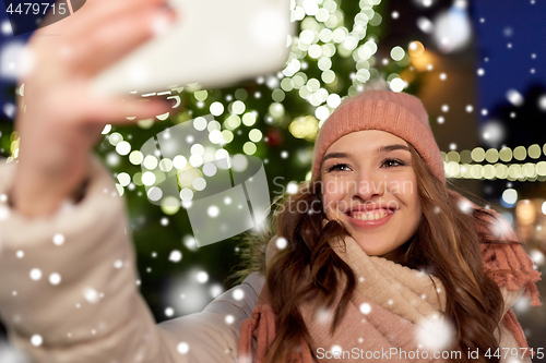 Image of young woman taking selfie over christmas tree