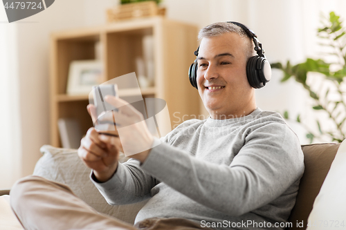 Image of man with smartphone and headphones at home