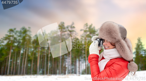 Image of happy woman with film camera over winter forest