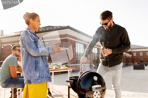 Image of friends cooking meat on bbq at rooftop party