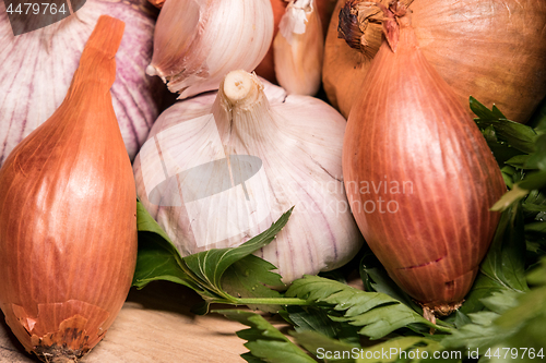 Image of garlic onion shallot parsley on a wooden board