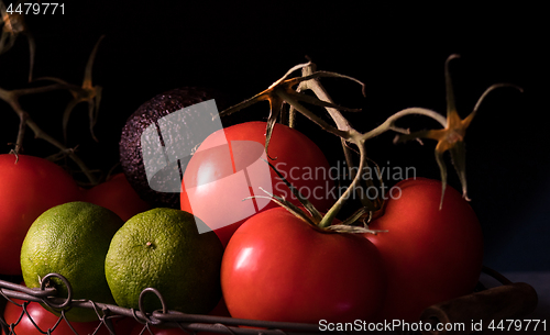 Image of big red and ripe tomatoes in an old basket on black background