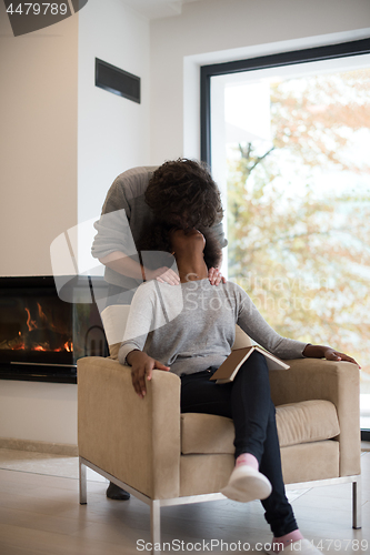 Image of multiethnic couple hugging in front of fireplace