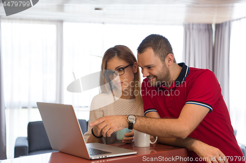 Image of couple drinking coffee and using laptop at home