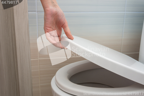 Image of The hand closes or opens the toilet lid