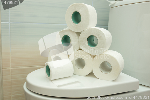 Image of The pyramid of toilet rolls lies on the lid of the toilet bowl