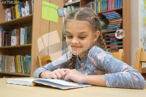 Image of A girl with a smile reads a book in the reading room