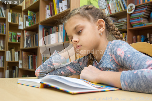 Image of A girl of ten years old is reading a book in the reading room