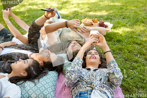 Image of friends with smartphones chilling at summer park