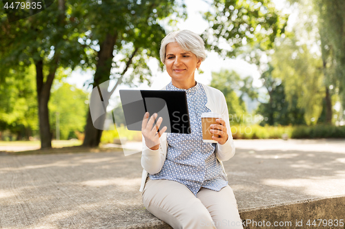 Image of old woman with tablet pc and coffee at summer park