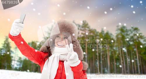 Image of happy woman taking selfie over winter forest