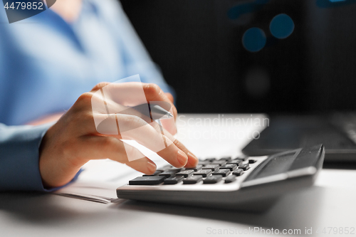 Image of businesswoman with calculator at night office