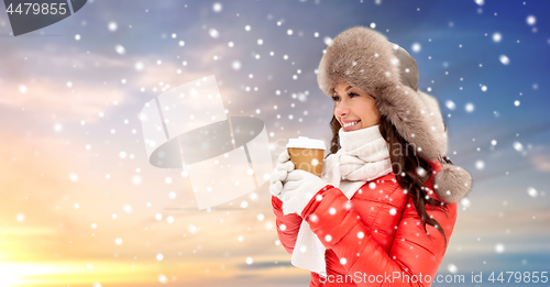 Image of woman in winter fur hat with coffee over snow