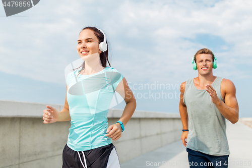 Image of couple with headphones running outdoors