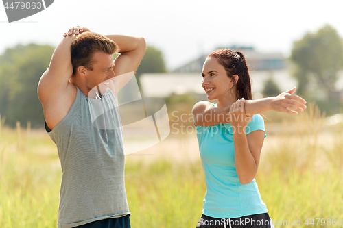 Image of smiling couple stretching outdoors